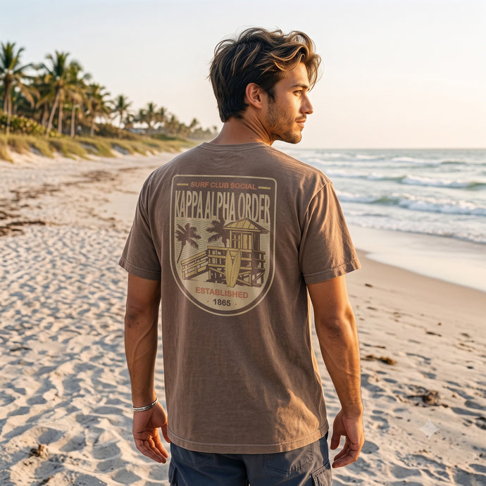 Model wearing the Surf Club Social T-shirt from the back while walking on a beach.