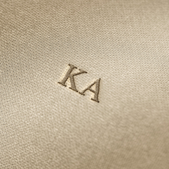 Soft beige fabric close-up showing a smooth, heavyweight knit texture with gentle folds and subtle draping.