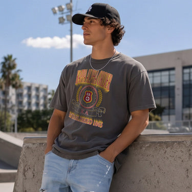 College-aged male wearing the fraternity Collegiate Crest Graphic Tee in charcoal grey, featuring vintage Kappa Alpha Order crest artwork on campus.