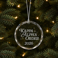 Limited Edition glass Christmas ornament with engraved design hanging on a decorated holiday tree