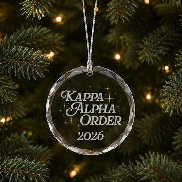 Limited Edition glass Christmas ornament with engraved design hanging on a decorated holiday tree